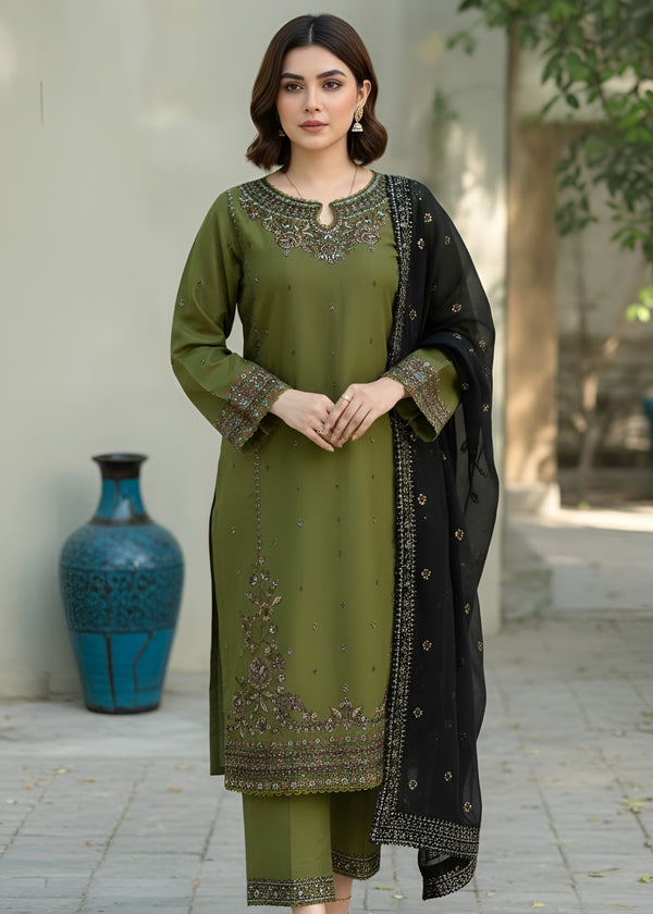 Woman wearing a green embroidered outfit with a black dupatta in an outdoor setting.