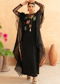 Woman wearing a black traditional outfit with sheer overlay in an indoor setting.