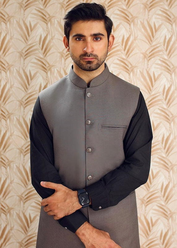 Man wearing a traditional outfit with a patterned background