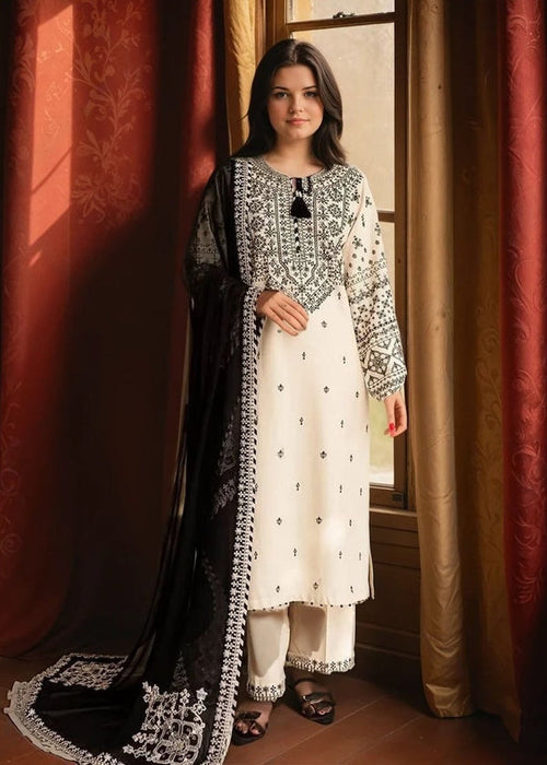 Woman wearing a traditional outfit with black and white embroidery in a room with red curtains.