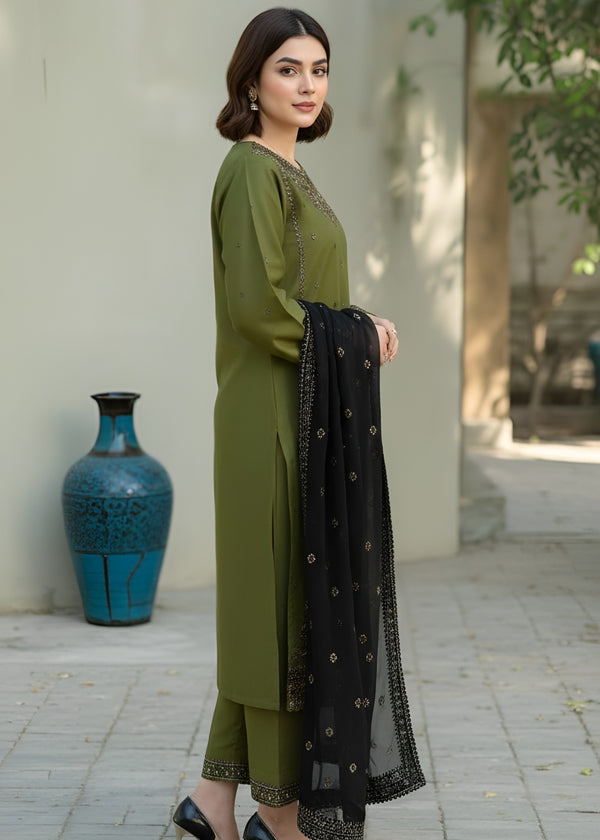 Woman in green traditional outfit with black dupatta standing outdoors.
