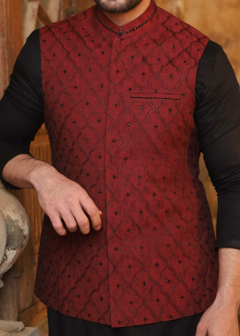 Man wearing a red embroidered vest over a black shirt with a blurred background