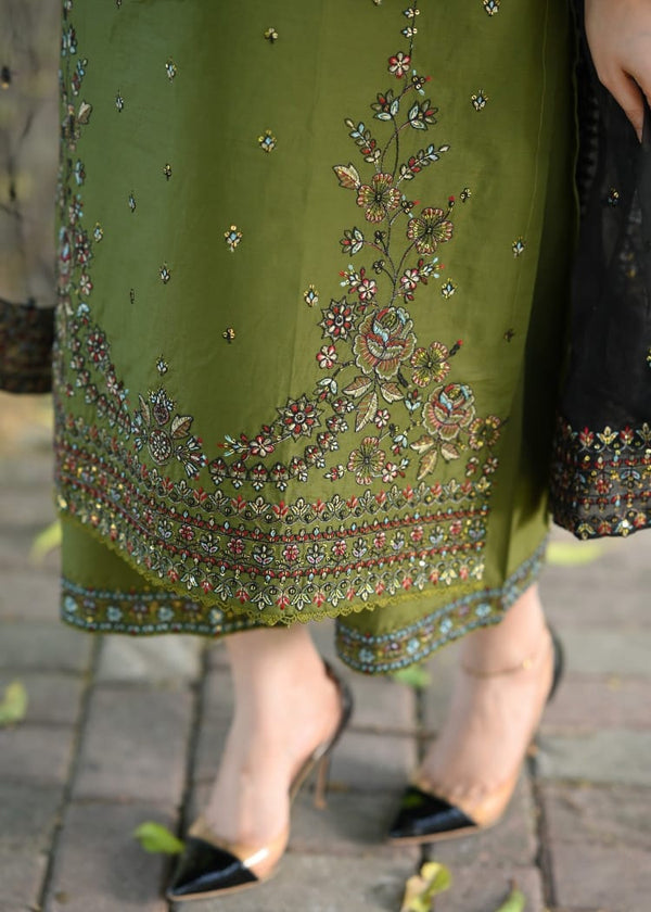 Green embroidered garment with floral patterns on a blurred outdoor background